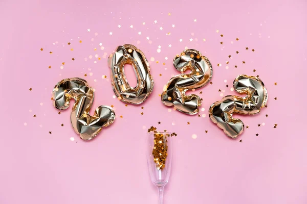 2021 altın folyo balon numaraları, şampanya, yıldız konfetileri, kurdeleler ve bokeh. Üst yatay görünüm fotokopi alanı yeni yıl ve tatil kavramı.