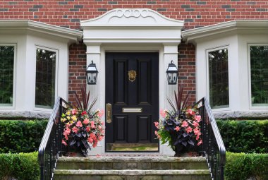 Renkli çiçeklerle dolu eski tuğla evin ön kapısı.