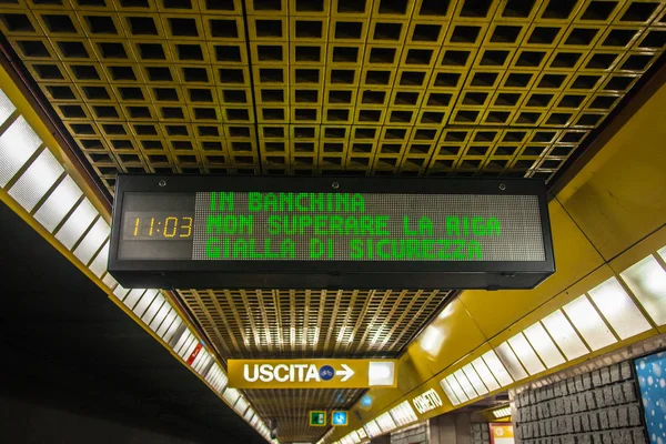 electronic sign placed on the ceiling of the Milan subway. waiting for the Milan subway to pass through the crowd of travelers