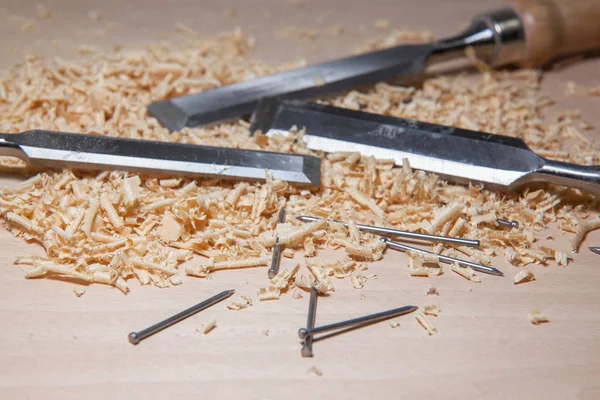 Table with chisel blades and shavings of wood sawdust and nails work of an artisan carpenter.