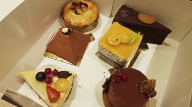 Bir kutuda bir dizi kek. Meyveler pastayı süslüyor..