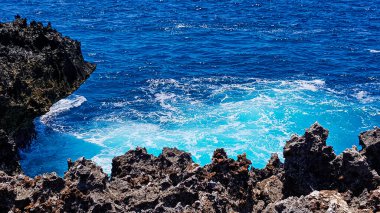 Turkuaz mavi deniz volkanik kayalar tarafından kırılır..