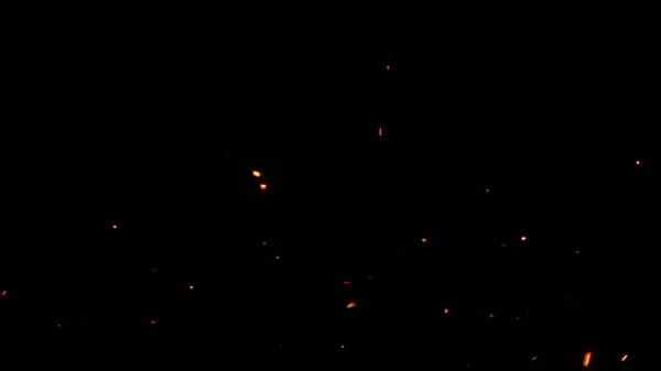 Fliegen glühender Feuerfunken mit schwarzem Hintergrund — Stockfoto