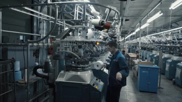 Un hombre prepara un lugar de trabajo en la fábrica de ropa — Vídeo de stock