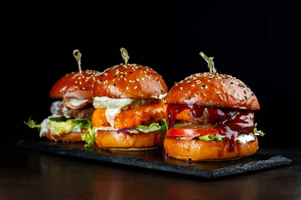 Pon hamburguesas con carne. Sobre un fondo negro . — Foto de Stock