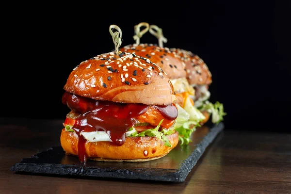 Pon hamburguesas con carne. Sobre un fondo negro . — Foto de Stock