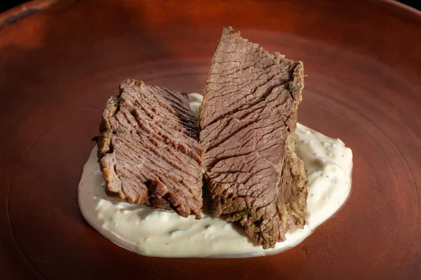 Kil tabağa üzerinde biftek. Krema sos ile kaplı.