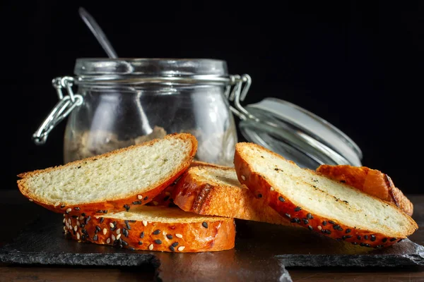 I pani tostati sono disposti su un'ardesia nera, un primo piano di un panino con sesamo . — Foto Stock