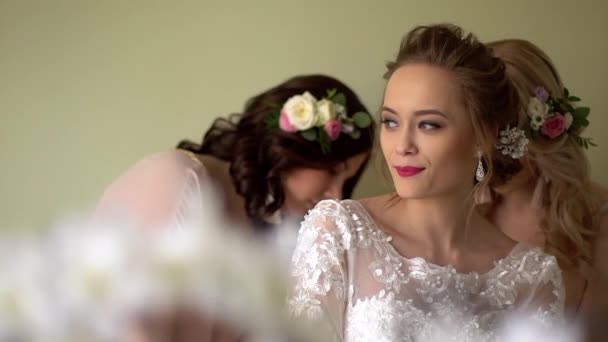 2 つのガール フレンドは、花嫁をドレスアップ ヘルプします。みんなが笑っている、女の子は、花で飾られました。. — ストック動画