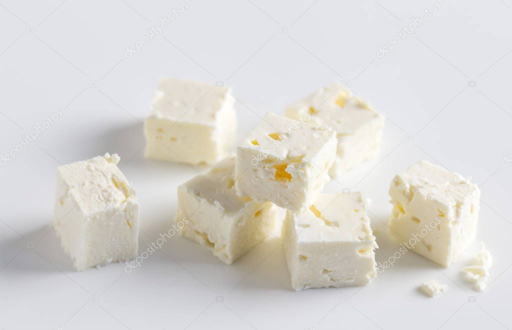 Feta cheese cubes on white background with selective focus and space for text