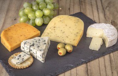 Peynir kurulu dört peynir, yenibahar ile gouda, gouda kimyon tohumu, camembert ve rokfor mavi peynir ile yakın çekim rustik ahşap arka plan üzerinde