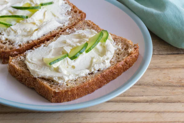 Cottage cheese bread - Slices of whole wheat bread with creamed cottage cheese and cucumber slices on wooden table