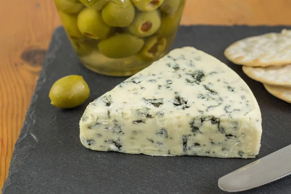 Cuña Queso Azul Con Tarro Desenfocado Aceitunas Verdes Galletas Saladas — Foto de Stock