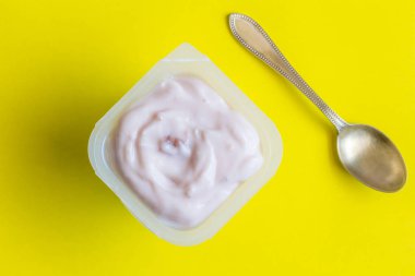 Çilekli yoğurt ve küçük gümüş kaşık yakın kadar - üstten görünüm fotoğraf sarı zemin üzerine yoğurt yoğurt Kupası