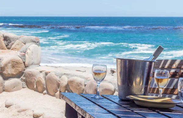 Wine glasses at a rustic beach restaurant table facing the Atlantic Ocean - Image