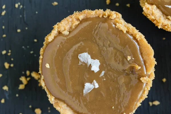 Salted caramel tart on rustic black background - Top view image — Stock Photo, Image