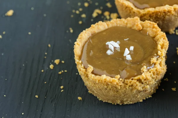 Tartaleta de caramelo con cristales de sal espolvoreado en la parte superior, aislado en negro — Foto de Stock