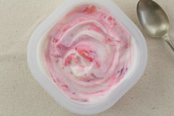 Tazza di yogurt con yogurt naturale alla fragola in stile greco roteato con cucchiaino piccolo — Foto Stock