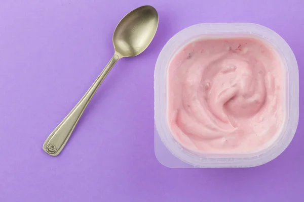 Yogurt cup with pink strawberry yogurt and small silver spoon — Stock Photo, Image
