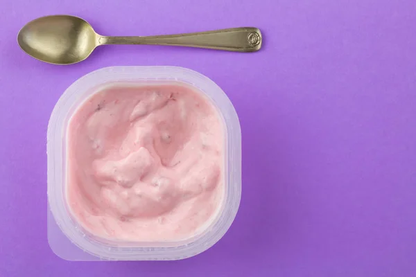Strawberry yogurt in plastic cup isolated on lilac background - — Stock Photo, Image