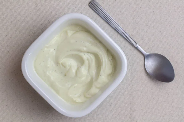 Чаша вершкового ванільного йогурту з ложкою на лляній тканині столу — стокове фото
