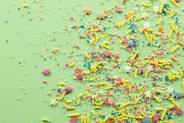 Soluk yeşil arka plan üzerine serpin - Çeşitli renkli kek tepesi sprinkles