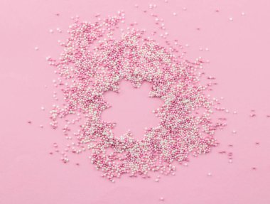 Pembe ve beyaz yenilebilir incili pembe arka plan üzerine serpiştirilmiş - Kek tepesi sprinkles