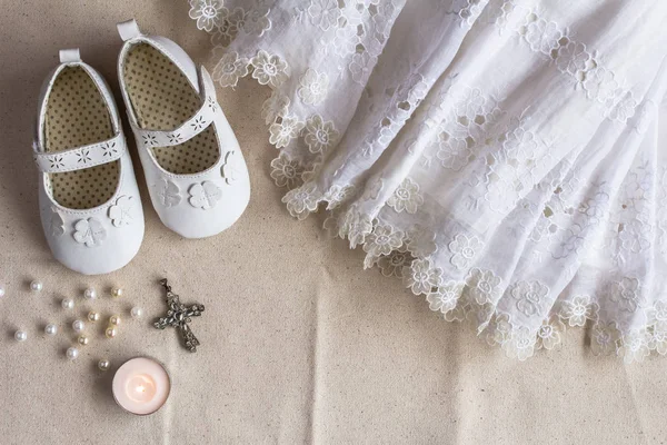 Christening background with baptism dress, shoes, candle and cross pendant — Stock Photo, Image