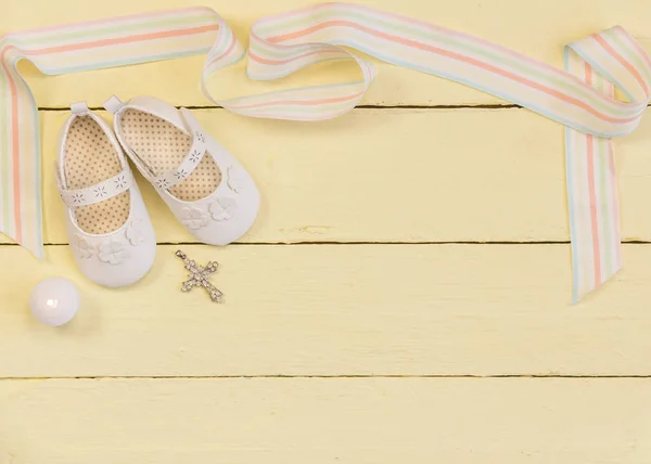 Fundo batizado com sapatos brancos, vela e pingente de cristal cruz — Fotografia de Stock