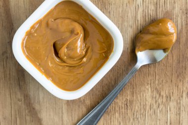 Karamel kaşıkta ve kare kase de rustik ahşap üzerinde tuz pul ile ahşap