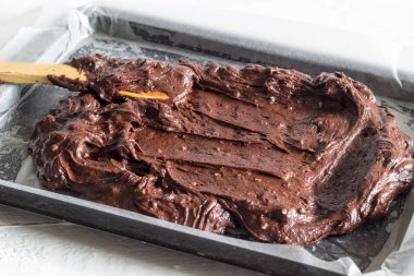 Çikolatalı brownie kek hamuru yağlı kağıt fırın tepsisine kaplı yerleştirilen ediliyor