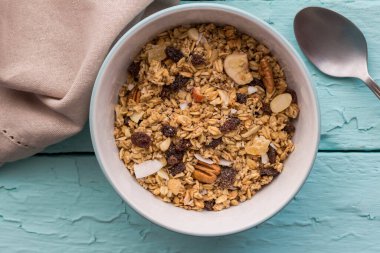 Kuru üzümlü granola, kurutulmuş muz, fındık. Kırsal mavi masa arka planında müsli kahvaltısı.