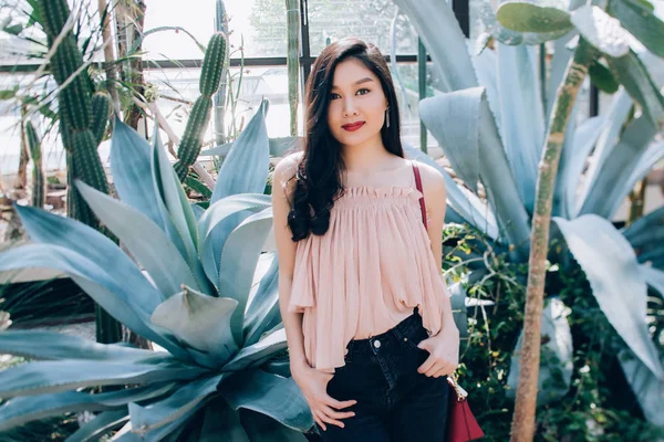 Photo Session of a beautiful young girl in blooming magnolia, cactus and other vegetation.