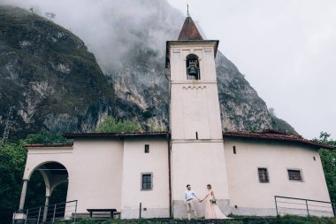 Yeni evliler doğada yürüyüş. Damat ve gelin kilisenin arka planı.