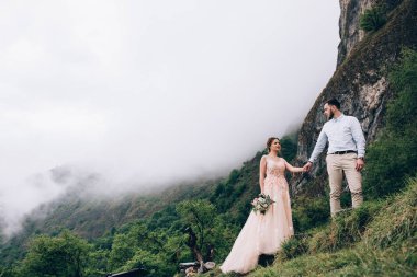 Yeni evliler doğada yürüyüş. Damat ve gelin dağlar ve deniz arka planı.