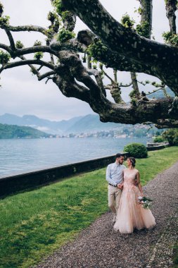 Yeni evliler doğada yürüyüş. Damat ve gelin dolgu, denizin kenarında park boyunca yürümek.