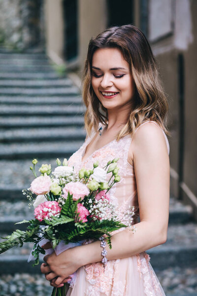 A bride in a white dress is holding a beautiful wedding bouquet.