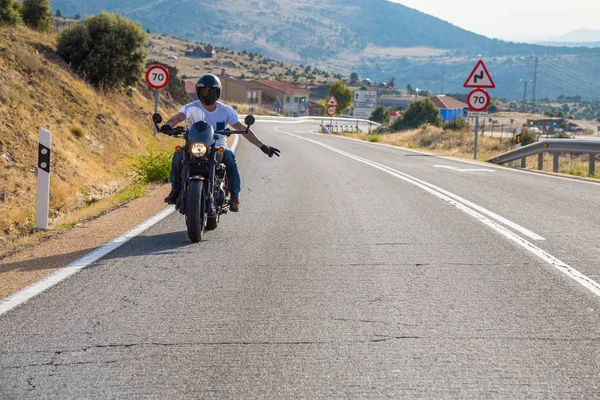 Genç adam dağlarda yolda güneşli bir günde bir motosiklet sürme. 