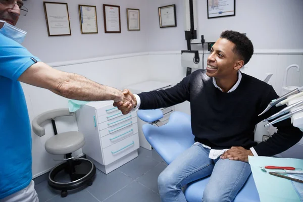 Afrikalı-Amerikalı genç adam kırpma diş hekimi ziyaret tıbbi klinikte sahip el sallayarak. 