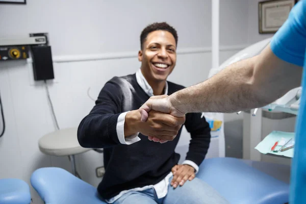 Afrikalı-Amerikalı genç adam kırpma diş hekimi ziyaret tıbbi klinikte sahip el sallayarak. 