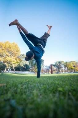 Parkour yaparken amut sokakta çimenlerin üzerinde yapan genç erkek.