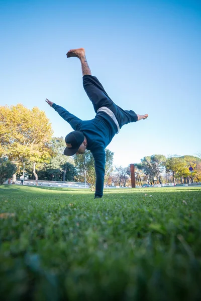 Young man doing handstand on grass in the street while doing parkour.