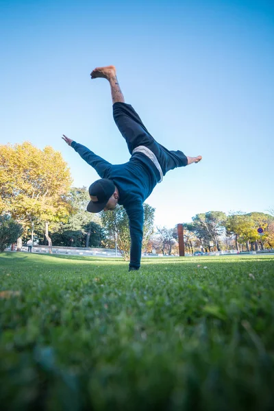 Parkour yaparken amut sokakta çimenlerin üzerinde yapan genç erkek.