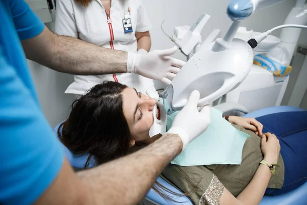 ホワイトニングの歯科医で治療を受ける若い女性 — ストック写真