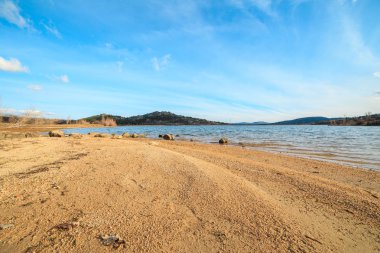 Mavi gökyüzü ile güneşli bir gün batımında dağlarda güzel göl 