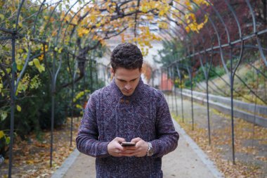 Sonbaharda bir parkta telefonda konuşurken yakışıklı genç