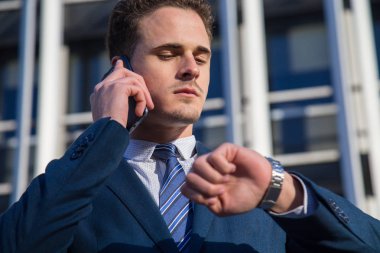 Ciddi işadamı saat telefonda konuşurken kontrol