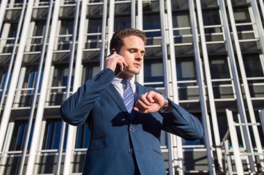 Ciddi işadamı saat telefonda konuşurken kontrol