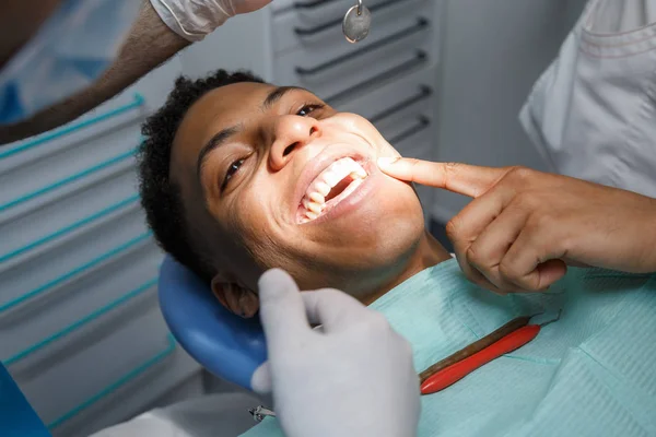 Mutlu Afro-Amerikan delikanlı ağız boşluğuna inceleyerek Doktor süre yaralayıcı diş gösteren dişçi koltuğu