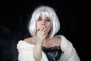 Puro sigara ve kamera siyah arka plan üzerinde dururken bakarak kostüm çekici genç kadın